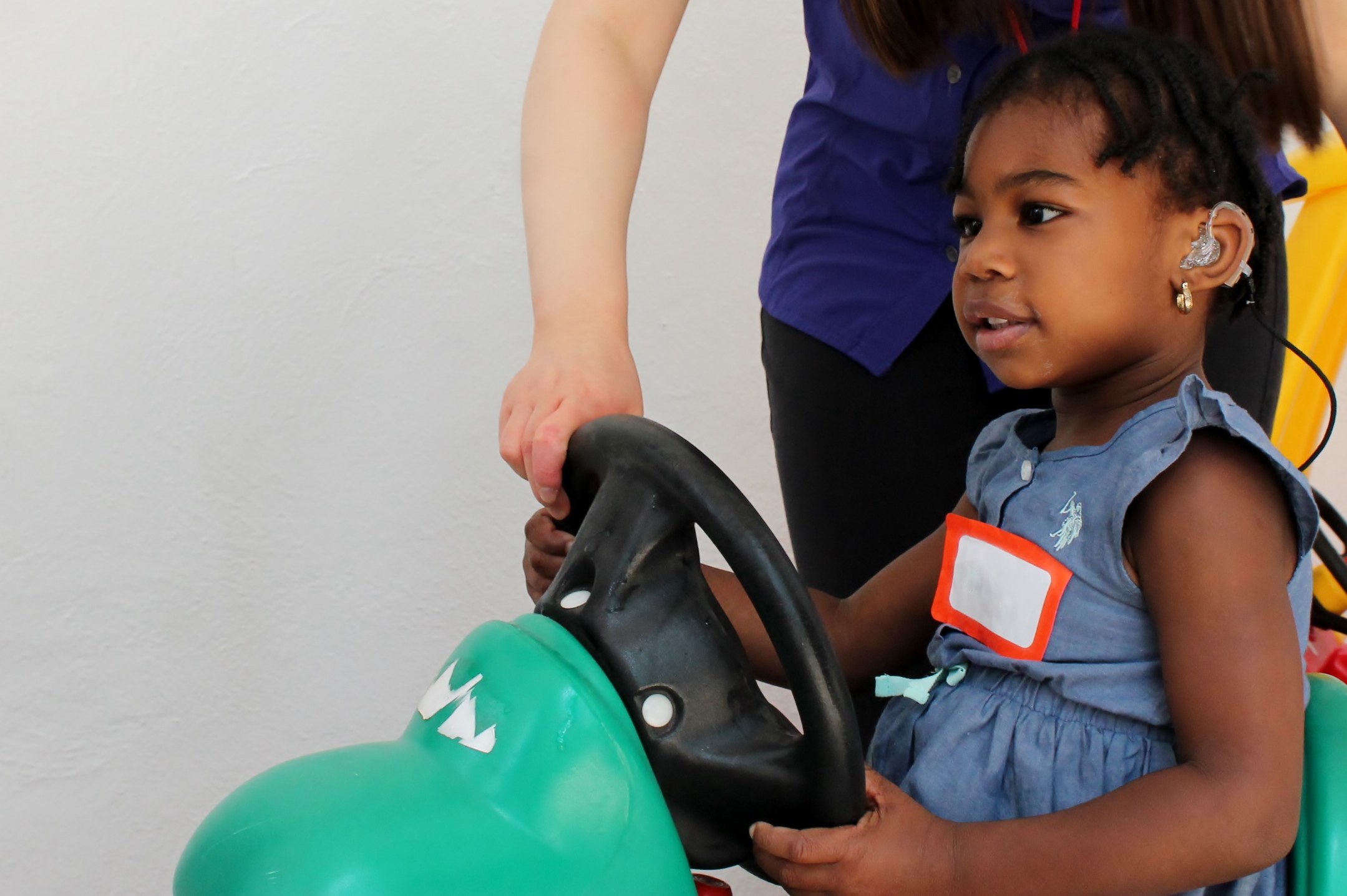 Child with CI at MCICE Summer intensive program driving play car