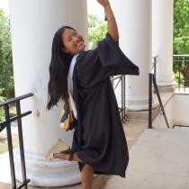 HESP '26 SLP MA graduate in master's regalia, raising her cap to the air and looking over her shoulder. 