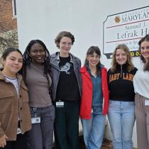 SIGNA coaches stand together outdoors beside a University of Maryland Samuel J. LeFrak Hall sign, smiling at the camera.