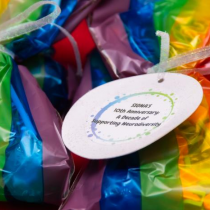 Close-up of colorful rainbow-wrapped items with a round white tag that reads, “SIGNA’s 10th Anniversary: A Decade of Supporting Neurodiversity.”