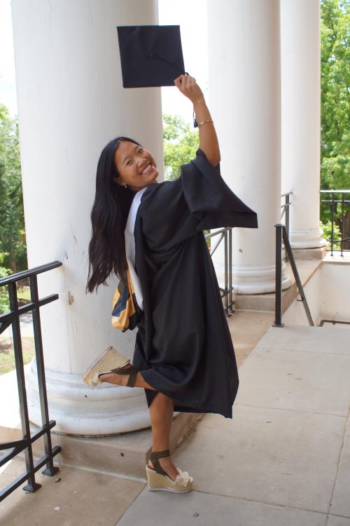HESP '26 SLP MA graduate in master's regalia, raising her cap to the air and looking over her shoulder. 