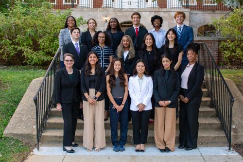 Group photo of BSOS DSAC standing on outdoor steps in front of a brick campus building, dressed in professional attire and smiling at the camera.