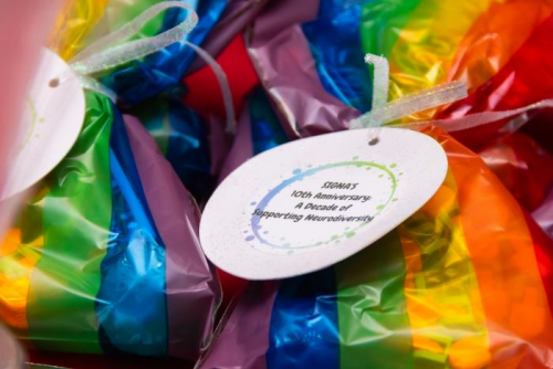 Close-up of colorful rainbow-wrapped items with a round white tag that reads, “SIGNA’s 10th Anniversary: A Decade of Supporting Neurodiversity.”