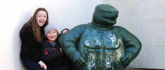 A smiling HESP student and LEAP student pose next to the Testudo statue, with the child leaning against the statue and both facing the camera.